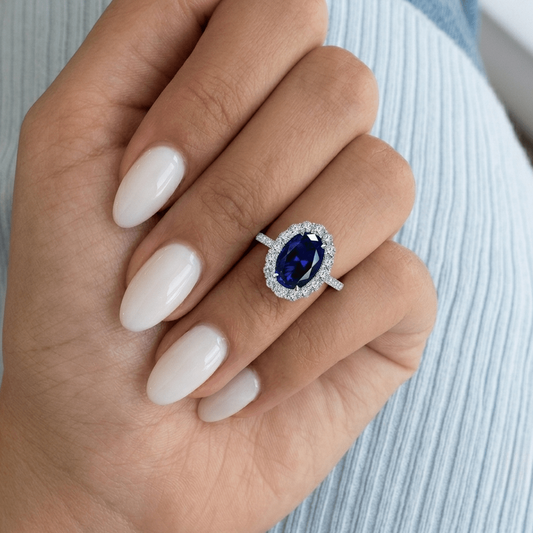 Blue sapphire halo engagement ring worn on hand, showing the stone's size and royal blue colour