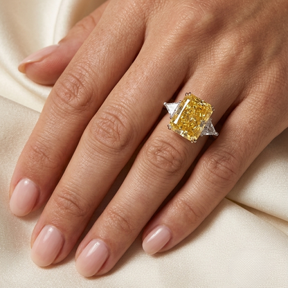 Hand wearing a yellow diamond ring on a beige fabric background