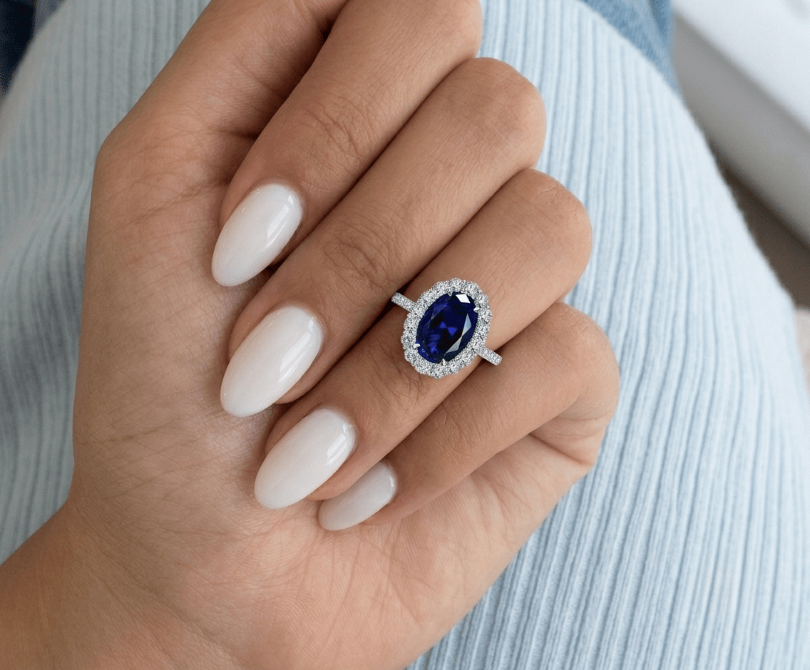 Blue sapphire halo engagement ring worn on hand, showing the stone's size and royal blue colour