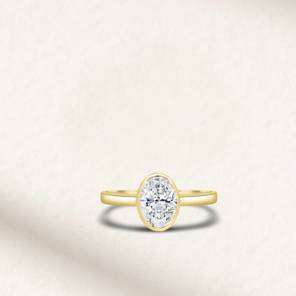 4 carat oval bezel set engagement ring in yellow gold with diamond simulant – modern statement ring on white background.