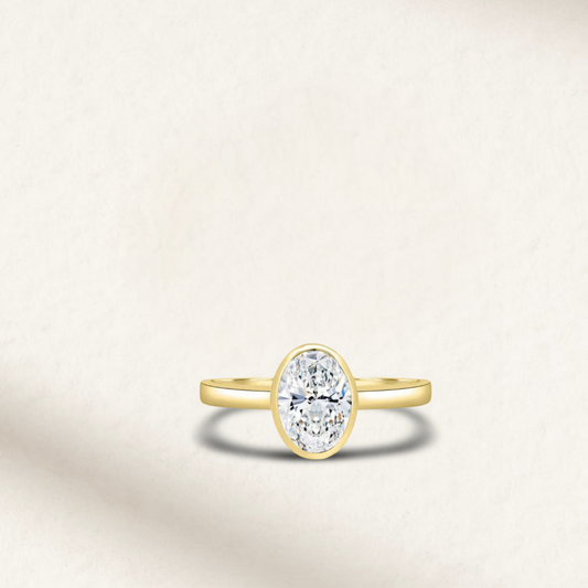 4 carat oval bezel set engagement ring in yellow gold with diamond simulant – modern statement ring on white background.