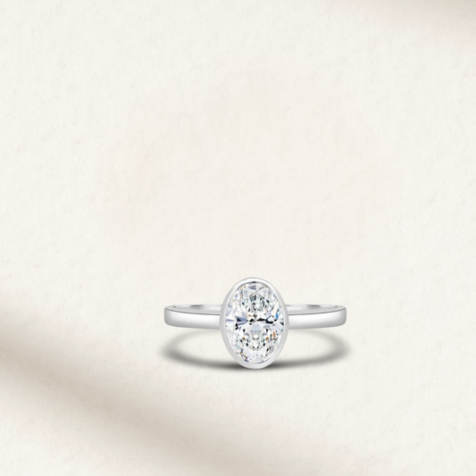 2 carat oval bezel set engagement ring in sterling silver featuring a diamond simulant with a minimalist bezel setting.