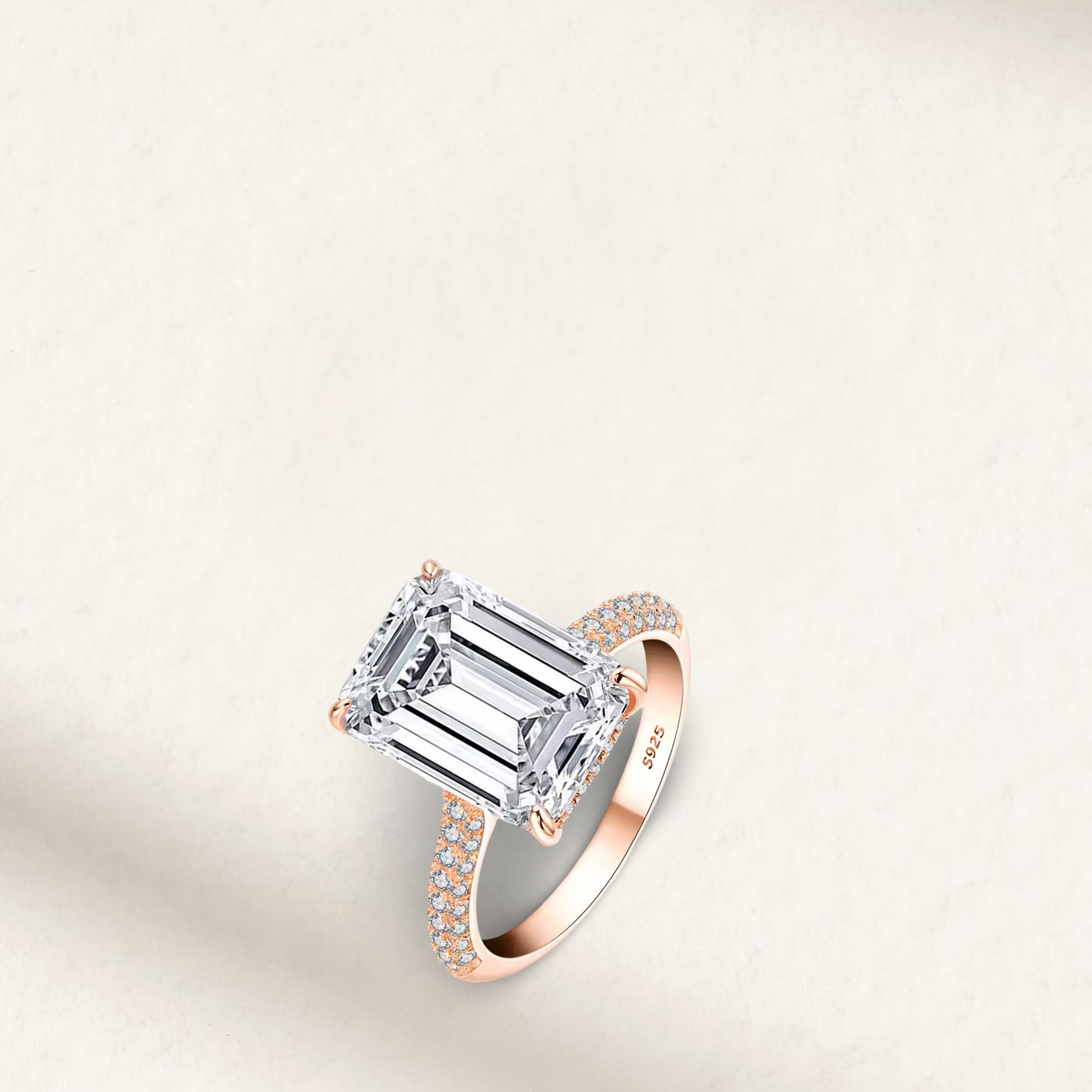 Emerald cut rose gold engagement ring with pavé band and hidden halo featuring a 6 carat diamond simulant set in 925 sterling silver.