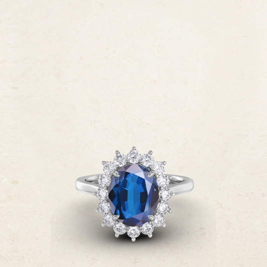 Princess Diana-inspired engagement ring dupe featuring a deep blue oval sapphire surrounded by a halo of sparkling diamonds in a classic silver setting.