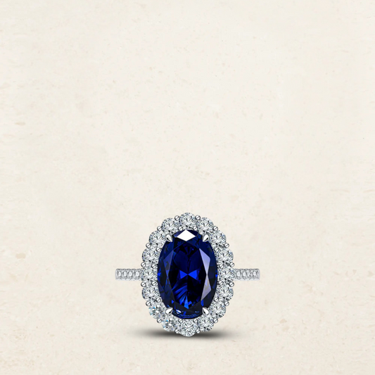 Princess Diana-inspired engagement ring dupe featuring a deep blue oval sapphire surrounded by a halo of sparkling diamonds in a classic silver setting.